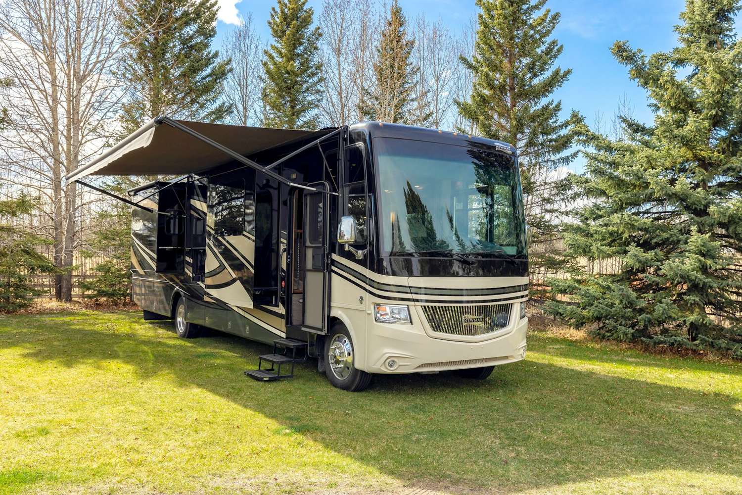 A motorhome parked with its awning out on a tidy grass lot