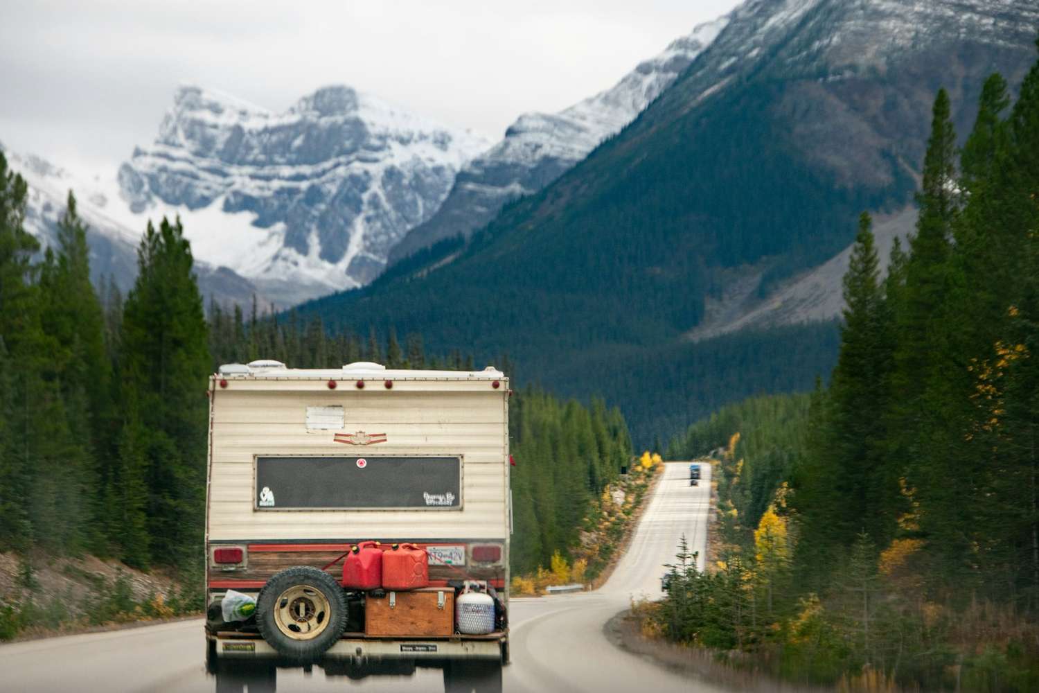 A motorhome on an open road heading toward snowy mountains